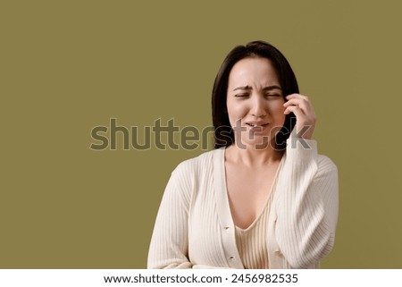 Portrait of upset asian woman crying isolated on green	