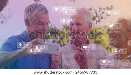 Image of media icons over happy senior diverse men using smartphone. social media and communication interface concept digitally generated image.