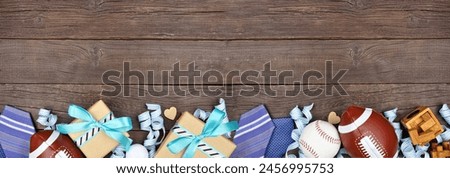 Fathers Day bottom border of gifts, ties, games and sport items. Top view on a rustic wood banner background. Copy space.