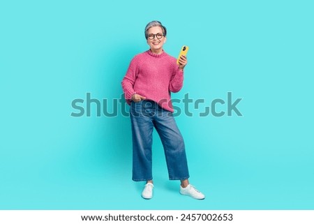 Full size photo of smart senior person dressed knit pullover jeans holding smartphone arm in pocket isolated on turquoise color background