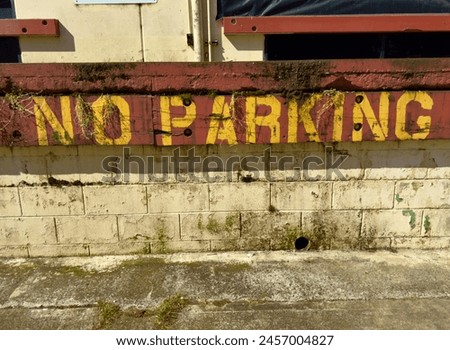 Yellow painted letters on red no parking sign exterior of building