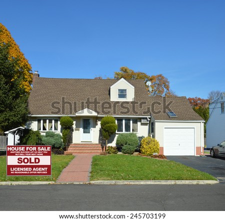 Real Estate sold (another success let us help you buy sell your next home) sign Suburban cape cod style home sunny clear blue sky autumn day residential neighborhood USA