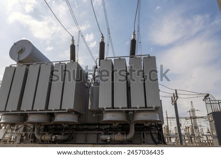 High voltage transformer against a blue sky background. Electric current redistribution substation