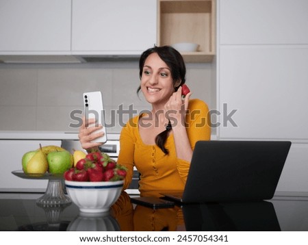 Woman make a pictures of strawberries at home kitchen