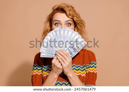 Photo portrait of lovely young lady money dollars cover hide face dressed stylish striped garment isolated on beige color background