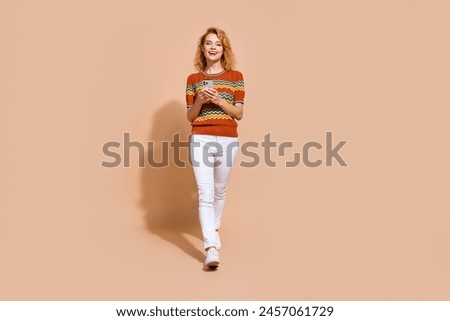 Full size photo of confident girl wear ornament t-shirt walk with smartphone chatting with friends isolated on beige color background