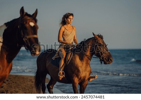 Beautiful young girl horseback riding on coastline at the beach during a sunset. Gorgeous woman in an attractive dress enjoying freedom at the seacoast with her horse. Copy space.