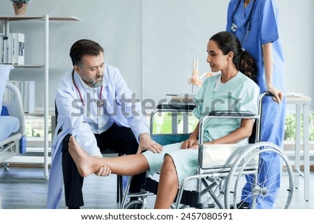 Therapist working on patient’s leg, guiding through physical therapy session, clinic setting evident. Physical therapist aids in leg extension exercise, gentle guidance, modern medical office ambiance
