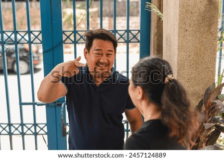 An Asian man mocks his wife's mannerisms during a heated debate near the gate of their home.