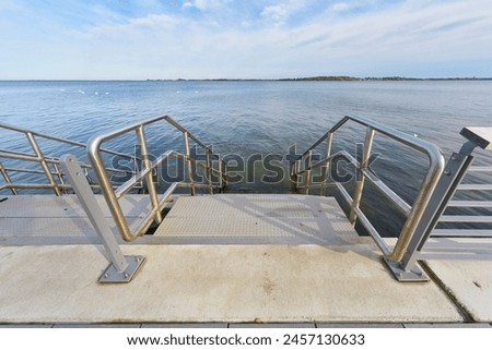  Bathing area with steps on the Sundpromenade in Stralsund in Germany. The island of Rügen on the horizon                               Royalty-Free Stock Photo #2457130633