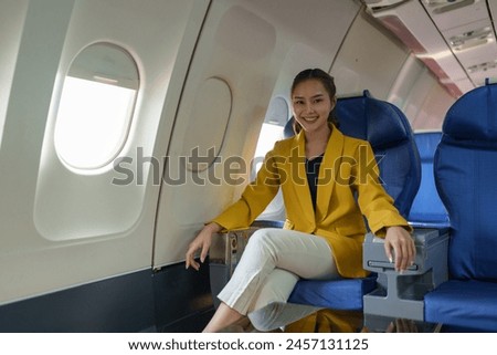 Confident businesswoman in formal attire sits smiling on a plane during a flight while traveling for work, travel, business, online abroad. Travel concept, business travel, work lifestyle.