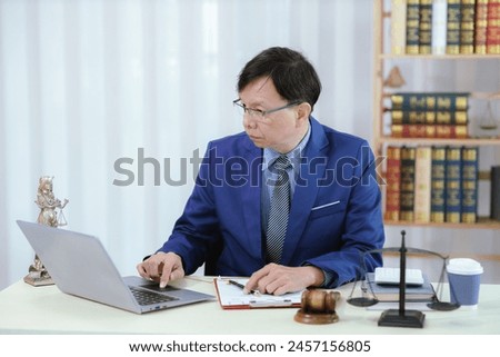 Lawyer sitting in his office On the table with a small hammer judge in court and the scales of justice The lawyer is drafting a contract for the client to sign with the defendant.
