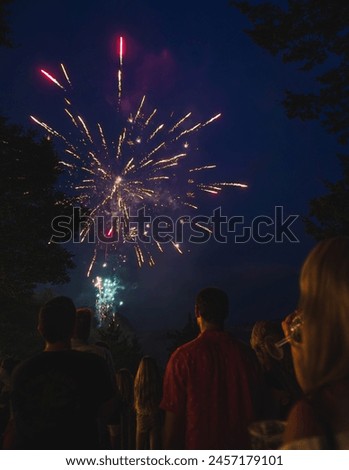 Fourth of July firework over river in Midwest with dark figures of people watching