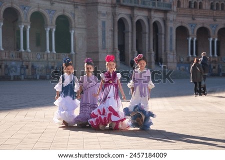 Four girls dancing flamenco, walking, in typical flamenco dress in a nice square in Seville. Dance concept, flamenco, typical Spanish, Seville, Spain. Royalty-Free Stock Photo #2457184009