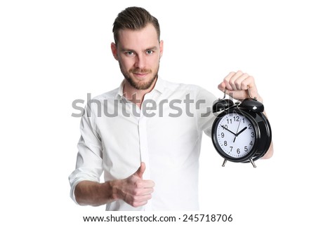 An attractive man wearing a white shirt holding a big clock, standing against a white background.