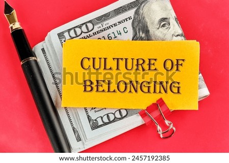 Culture of belonging symbol on a sticker lying on dollar bills on a red background, next to a fountain pen