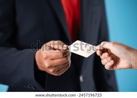 Credit card is in the hands of two hand holding it from different sides isolated on a blue color background.
