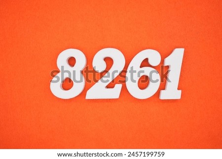 The number 8261 is made from white painted wood placed on a background of orange paper.