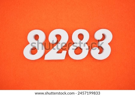 The number 8283 is made from white painted wood placed on a background of orange paper.