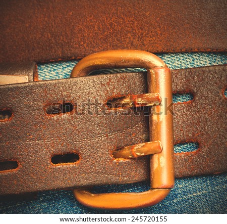 Vintage leather belt with a buckle on the background of denim. Instagram image style