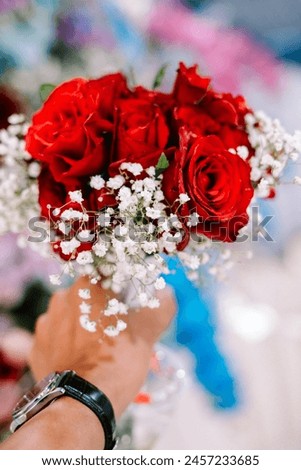 A person holding a bouquet of red roses, symbolizing love and affection, perfect for romantic gestures and special occasions.
