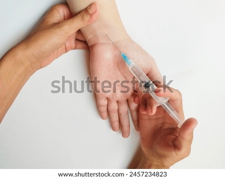 Cropped hands of a person injecting syringe over white background.