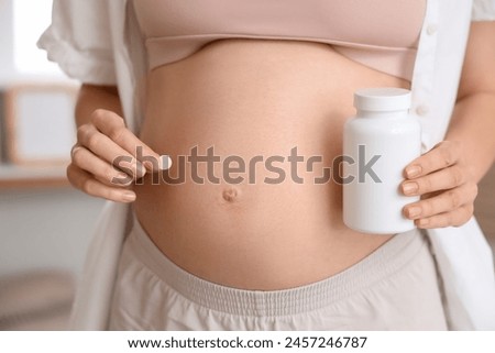 Young pregnant woman with pills in bedroom, closeup