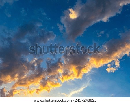 Stunning capture of sunset clouds painted with golden edges against a deep blue sky, perfect for illustrating majestic and tranquil scenes