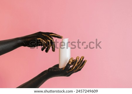 A Cosmetic glass tube in hands with black paint on her skin. Presenting luxury skincare products. Image for your design
