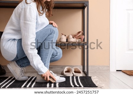 Young woman cleaning gumshoes with brush at home Royalty-Free Stock Photo #2457251757