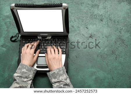 Soldier in uniform with military laptop on green grunge table