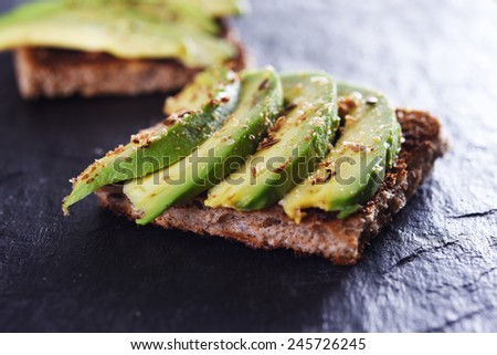 sliced avocado on toast bread with spices Royalty-Free Stock Photo #245726245