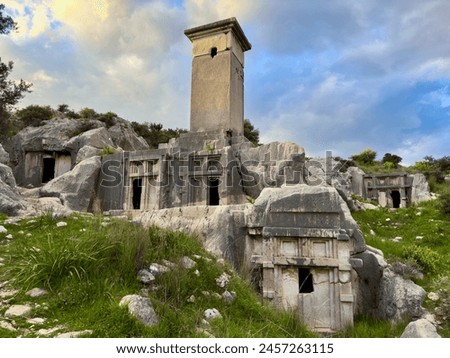 The ancient tombs of Xanthos in Kaş, Antalya, Turkey, are nestled among rocky landscapes and lush greenery, embodying historical architecture and scenic beauty. Royalty-Free Stock Photo #2457263115