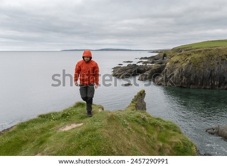 Hiker walking on the edge of cliffs on the sea coast