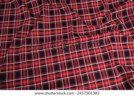 Texture drapery fabric with tartan plaid print in red, black and white colors, top view, textured background.