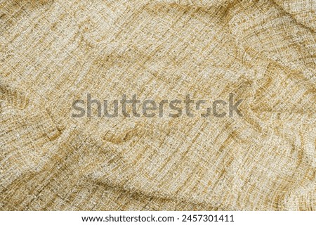 Texture of draped gold tweed woven fabric textile background, Chanel style classic fabric, top view.
