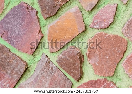 It is photo of colorful stones on green background. Its close up of multicolored stone wall of building. It is photo of mosaic tile floor. It's view of the wall texture.