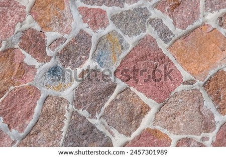It's close up view of colorful wall. Its photo of multicolor stonewall. It is photo of multicolored srone wall. its view of red sidewalk. It's the view of mosaic stonewall