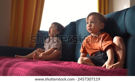 little children resting at home. happy and full of joy childhood, children's dream concept. a small boy and girl are sitting on a lifestyle blue sofa and enthusiastically watching cartoons on TV