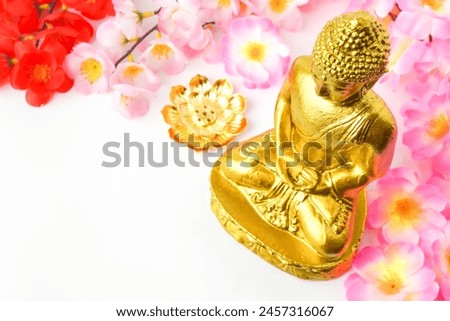 A golden statue of a Buddhist figure meditating decorate with colorful flowers facing the front isolated on white background. Concept for Vesak Day and Enlightenment Day