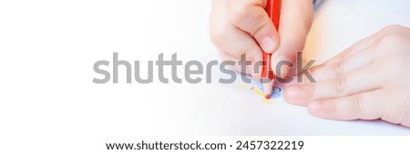Close-up of a child's hands drawing with colored pencils. Children's creativity and development, fine motor skills, learning to write and draw. Banner with free space for text
