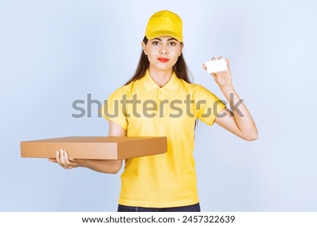 Image of young woman holding package and showing business card. High quality photo
