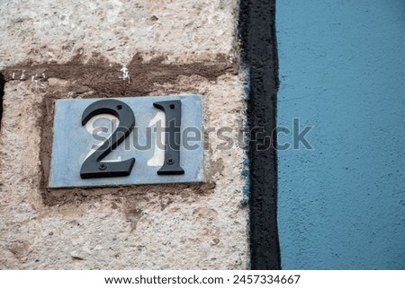 Isolated twenty one number. Street sign, house number. Stone and blue wall. 