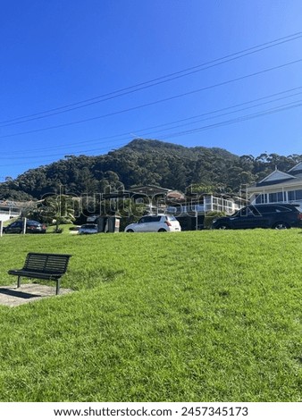 This is a photo with a bench and  view of the mountain in background and some house. 