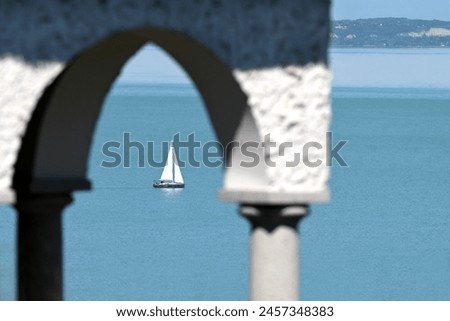 White sailing boat on lake Balaton through an arch from Tihany Royalty-Free Stock Photo #2457348383