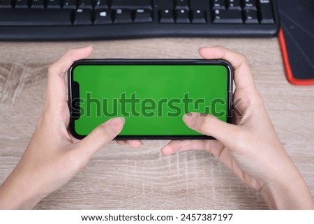 hand holding smart phone like play games with greenscreen and isolated on table