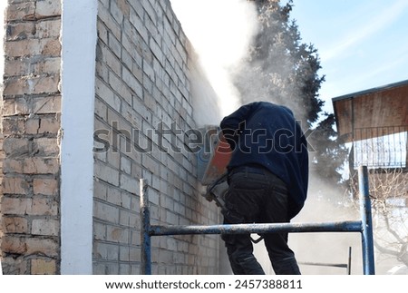 Cutting a hole in a brick wall using a wall cutter.