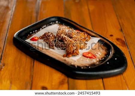 close-up on wooden table there is a prepared dish of chicken wings with sesame seeds