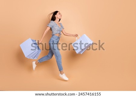 Photo of excited charming lovely woman wear blue trendy clothes going fast look empty space isolated on beige color background Royalty-Free Stock Photo #2457416155