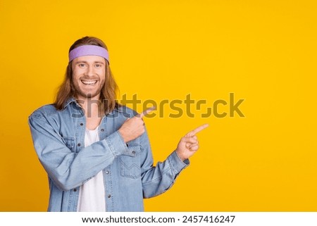 Photo portrait of attractive young hippie man point empty space wear trendy denim outfit isolated on yellow color background